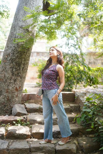 Full view of a sleeveless halter kurti in a rich navy and maroon geometric print, featuring a V-neckline and tailored waist. Paired with light blue straight-fit jeans and juttis, the look blends traditional block printing with modern casual style