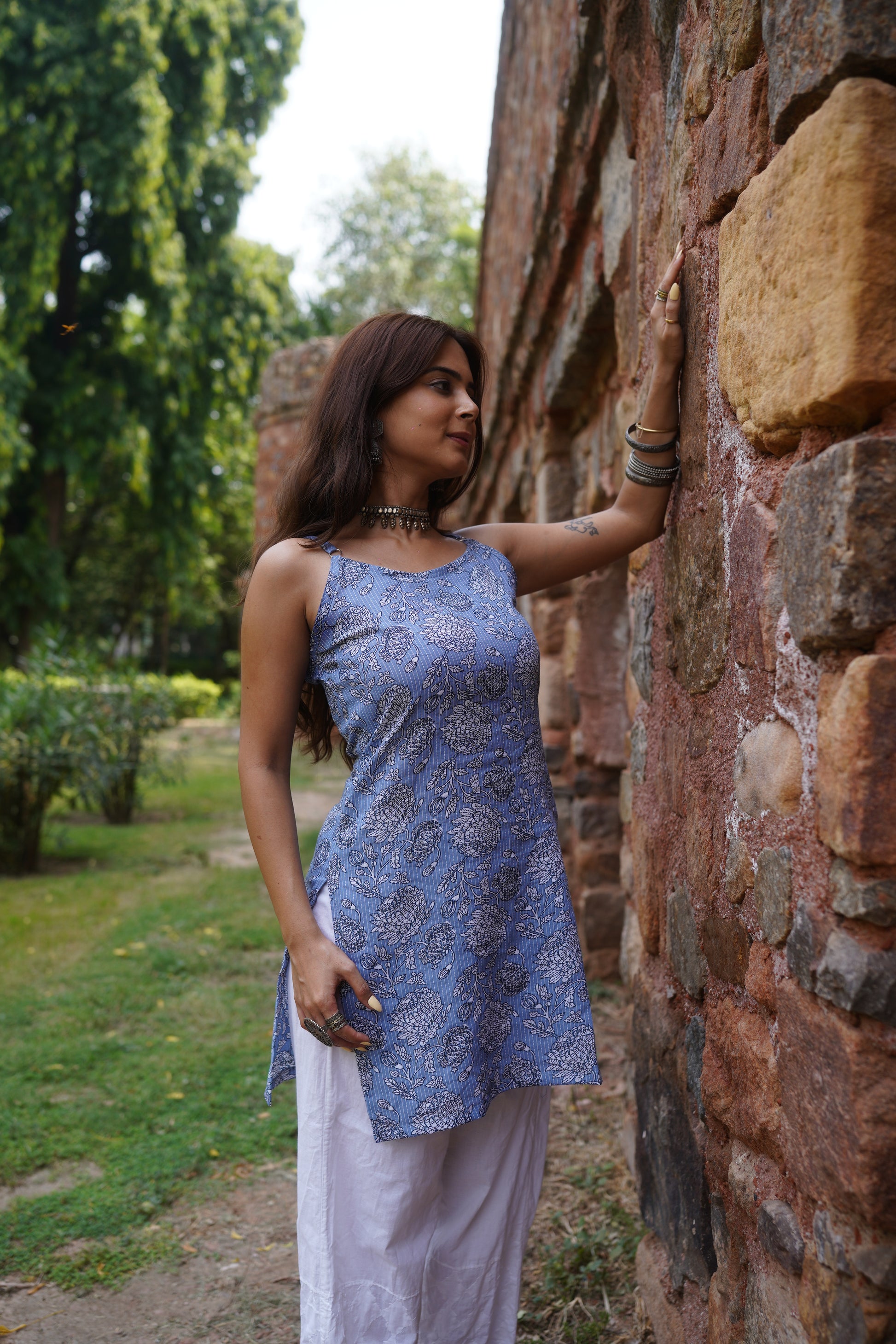 Sleeveless straight-cut kurti in a soft periwinkle blue featuring intricate white and black floral block print. Designed with side slits and a relaxed silhouette, the kurti is styled with white palazzo pants for an elegant, summer-ready ethnic look.